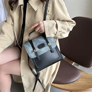 Close-up of color-block bag featuring black leather and blue denim texture with gold studs