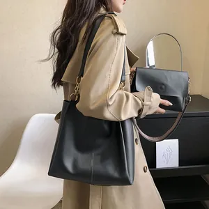 Detalle de set de bolso tote negro con anillos dorados y correa de hombro tejida