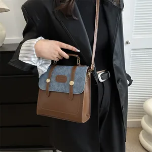 Detail of vintage patchwork handbag featuring brown leather and blue denim texture with gold studs