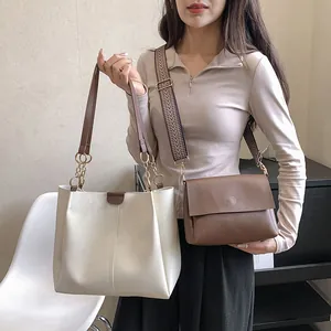 Detalle de un bolso tote crema con cadena y un bolso bandolera marrón con correa tejida