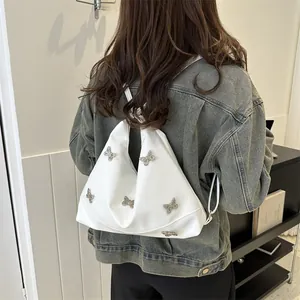 White faux leather shoulder bag with silver metal butterflies worn as an underarm bag