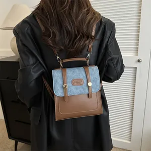 Detail of vintage patchwork mini backpack featuring blue denim flap and brown leather body