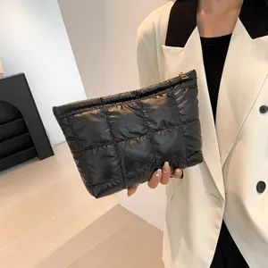 Detail of black quilted puffer clutch bag with gold zipper and stylish padded texture