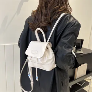 Detail of cream white leather backpack with drawstring closure and decorative beads