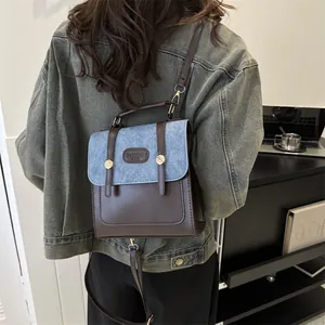 Detail of vintage patchwork backpack in brown leather and blue denim with metal buckle