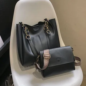 Detalle del conjunto de bolso tote negro con cadena dorada en una silla blanca