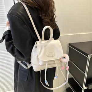 Detail of minimalist beige mini backpack with drawstring closure and pink plush charm