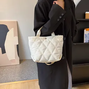 Detail of off-white quilted tote bag with silver snap button and textured rhombic pattern
