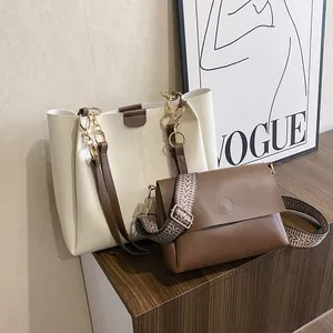 Detalle del bolso tote blanco roto y bolso bandolera marrón con correa tejida y herrajes oro