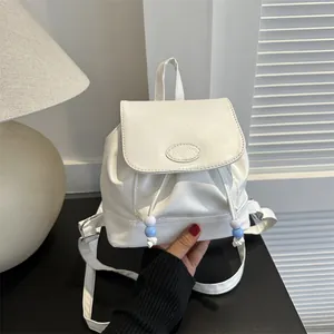 Dettaglio di un mini zaino bianco con chiusura a coulisse e decorazioni di perle