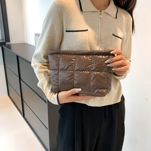 Detail of a dark brown quilted nylon clutch with padded texture and square pattern