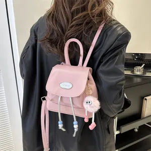 Pink PU leather mini backpack detail with silver metal brand plate and fuzzy charm