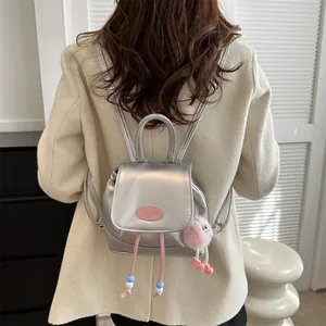 Detail of silver metallic mini backpack with pink plush charm and beaded drawstring