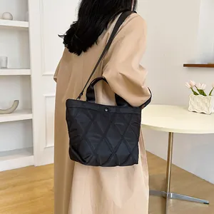 Detail of black quilted tote bag showing rhombus texture and adjustable shoulder strap