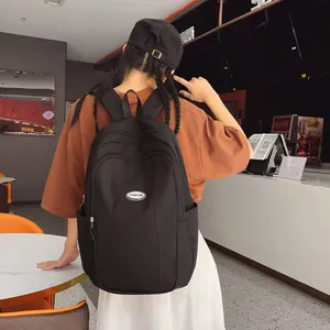 Rear view of a black nylon backpack with Fashion patch worn in a modern cafe setting