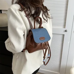 Detail of a brown leather and blue denim patchwork backpack with PAUTOR logo and drawstring