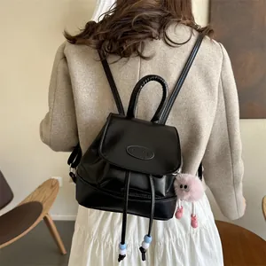 Side view of black leather backpack with PAUTOR logo and pink plush charm accessory