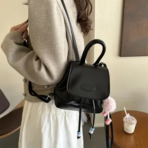 Detail of a minimalist black PU leather backpack with a plush pink pompom and handle
