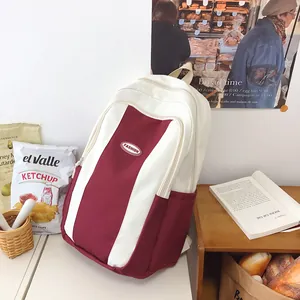 Detail view of large capacity canvas backpack featuring red and beige color-block design