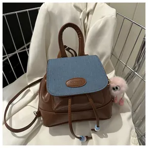 Detail of vintage patchwork backpack with brown leather, blue denim flap and plush charm