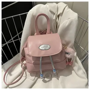 Detail of pink PU leather backpack with silver brand plate and cute pompom charm