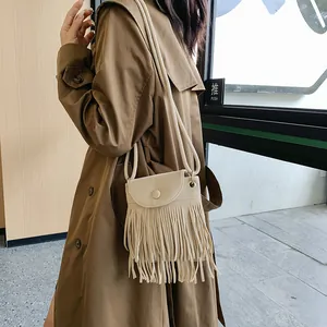 Borsa a tracolla beige chic con lunghe nappe su modella in trench marrone