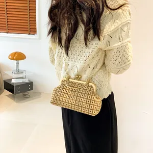 Detail of a brown woven knit crossbody bag with golden clasp and chain on a female model