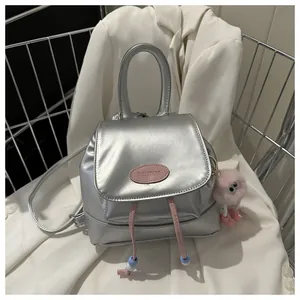 Detail of silver metallic mini backpack with pink drawstring and plush monster charm