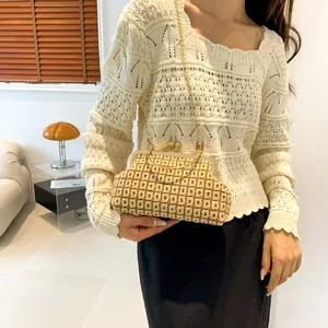 Close-up of woven beige clutch featuring a vintage metal clasp and a gold chain strap