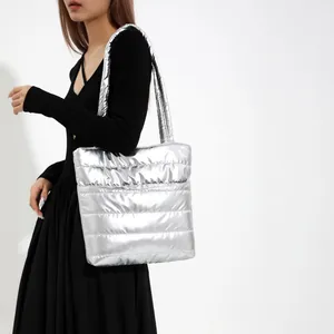 Sac fourre-tout argenté matelassé à fini métallisé porté par un mannequin en robe noire