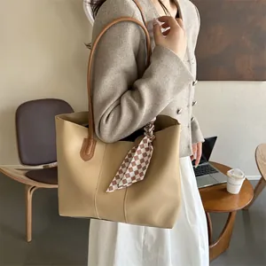 Dettaglio della borsa tote in pelle albicocca con spalline marroni e foulard a scacchi