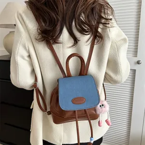 Mini brown leather and blue denim backpack for women with a cute pink plush charm