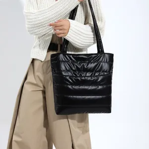 Détail d'un sac cabas noir matelassé montrant la texture douce et le nylon brillant