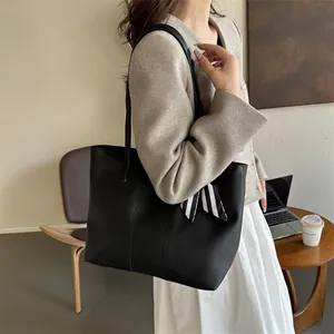 Dettaglio di una grande borsa tote nera con nastro di seta e trama in pelle