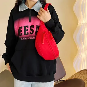 Détail d'un sac bandoulière rouge vif avec fermeture éclair et texture en nylon durable
