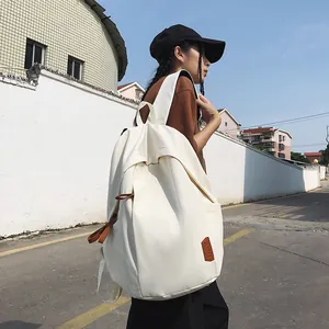 Detailed side view of white nylon backpack with brown leather accents and adjustable straps