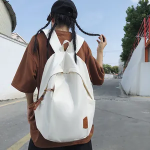 Detail of white nylon backpack featuring minimalist A letter print and brown leather tag