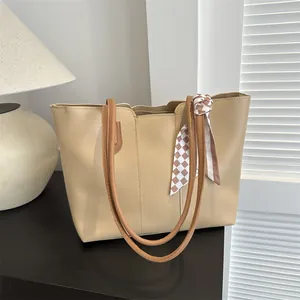 Dettaglio borsa tote in pelle PU beige con manici marroni e sciarpa di seta a scacchi