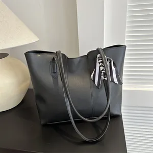 Dettaglio della borsa tote in pelle nera con manico decorato da un foulard a righe