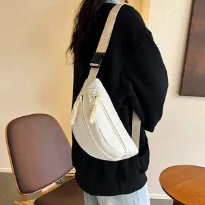 Détail d'un sac de poitrine en toile blanche avec bandoulière réglable et fermetures éclair