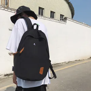Outdoor shot showing back view of black nylon backpack with padded shoulder straps