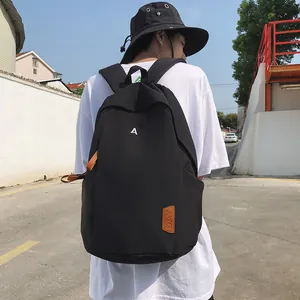 Detail of black nylon backpack with A letter embroidery and leather tag on male model