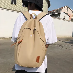 Detail of a beige nylon backpack with an embroidered letter A and brown leather zipper pull