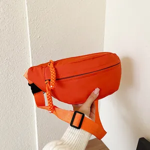 Détail du sac bandoulière orange vif avec tissu texturé et tirettes de fermeture tissées