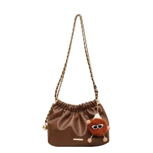 Brown faux leather cloud bag with gold chain strap and whimsical plush charm decoration