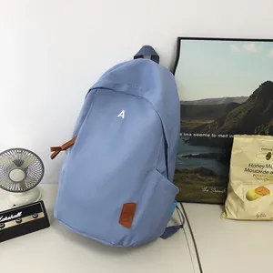 Close-up of light blue nylon backpack with brown leather zipper pulls and side pockets