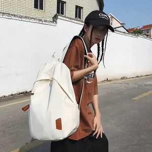 Minimalist white nylon backpack for women with leather logo patch and brown zipper detail