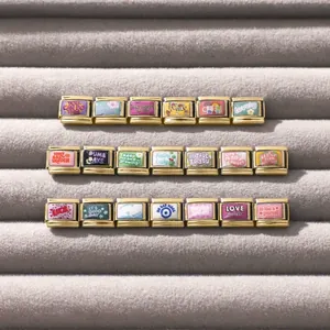Détail macro de vingt charms modulaires dorés pour bracelets italiens avec émail coloré