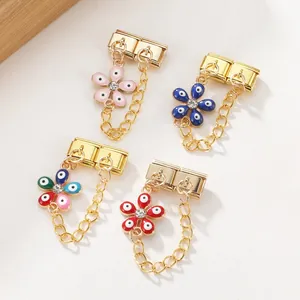Detail of four colorful enamel flower charms with evil eye motifs and gold-plated hooks