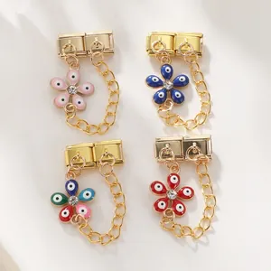 Macro detail of gold-plated flower charms with evil eye enamel and white rhinestones